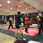 Adults training in kickboxing doing padwork drills in pairs